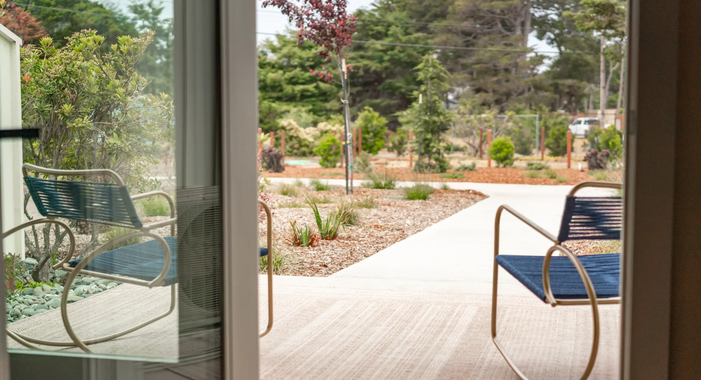 View from Mendocino hotel room patio with blue chairs overlooking landscaped garden