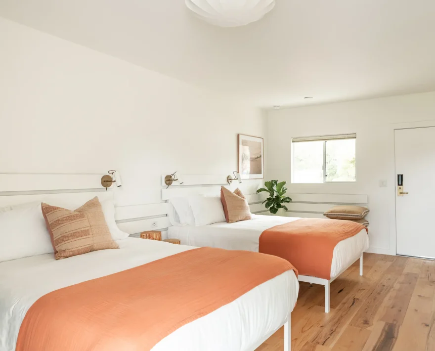Fort Bragg hotel with two queen beds, wood floors, and modern wall lighting