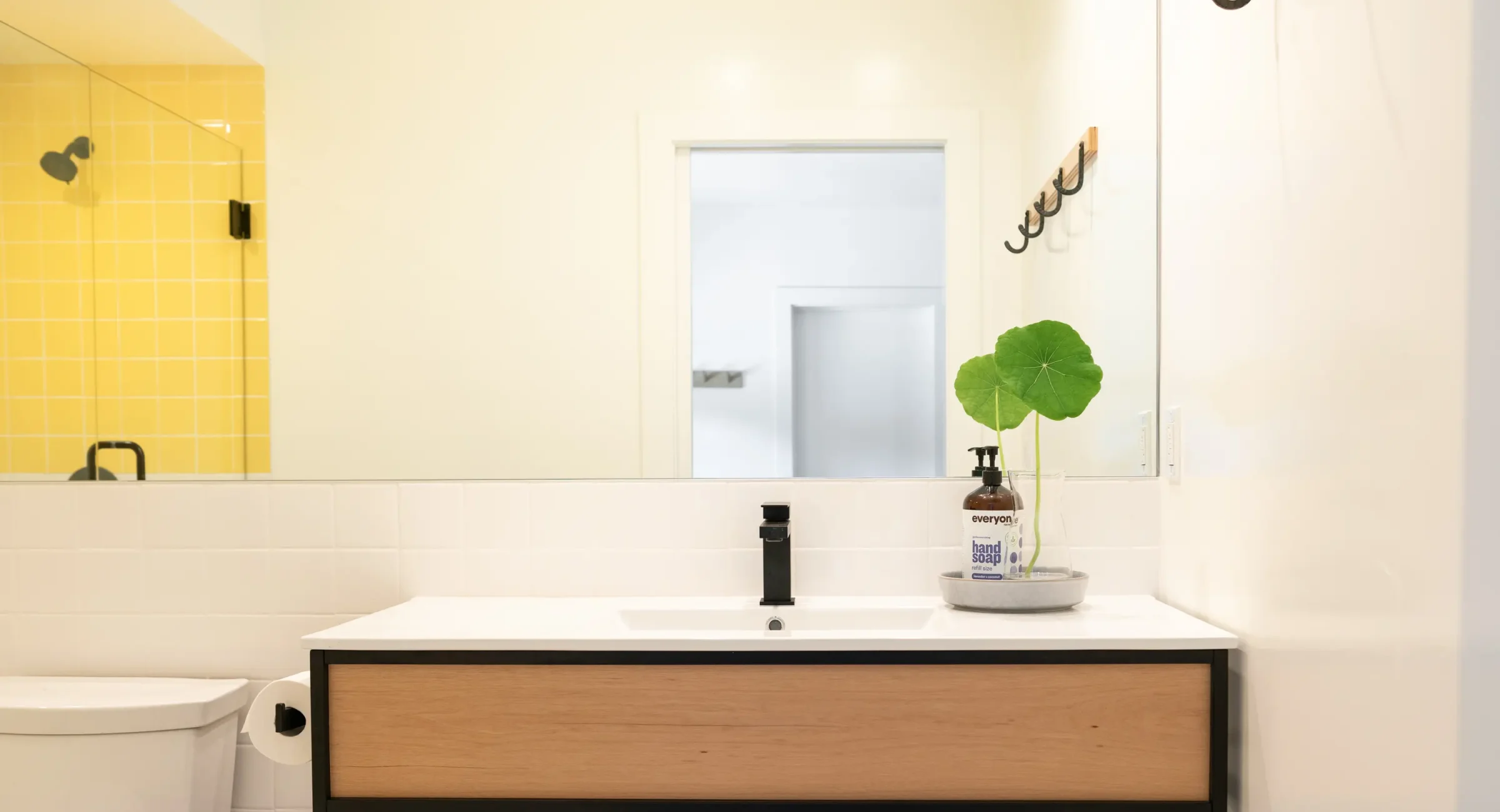 Suite bathroom at Mendocino boutique hotel with vanity sink and yellow tile shower