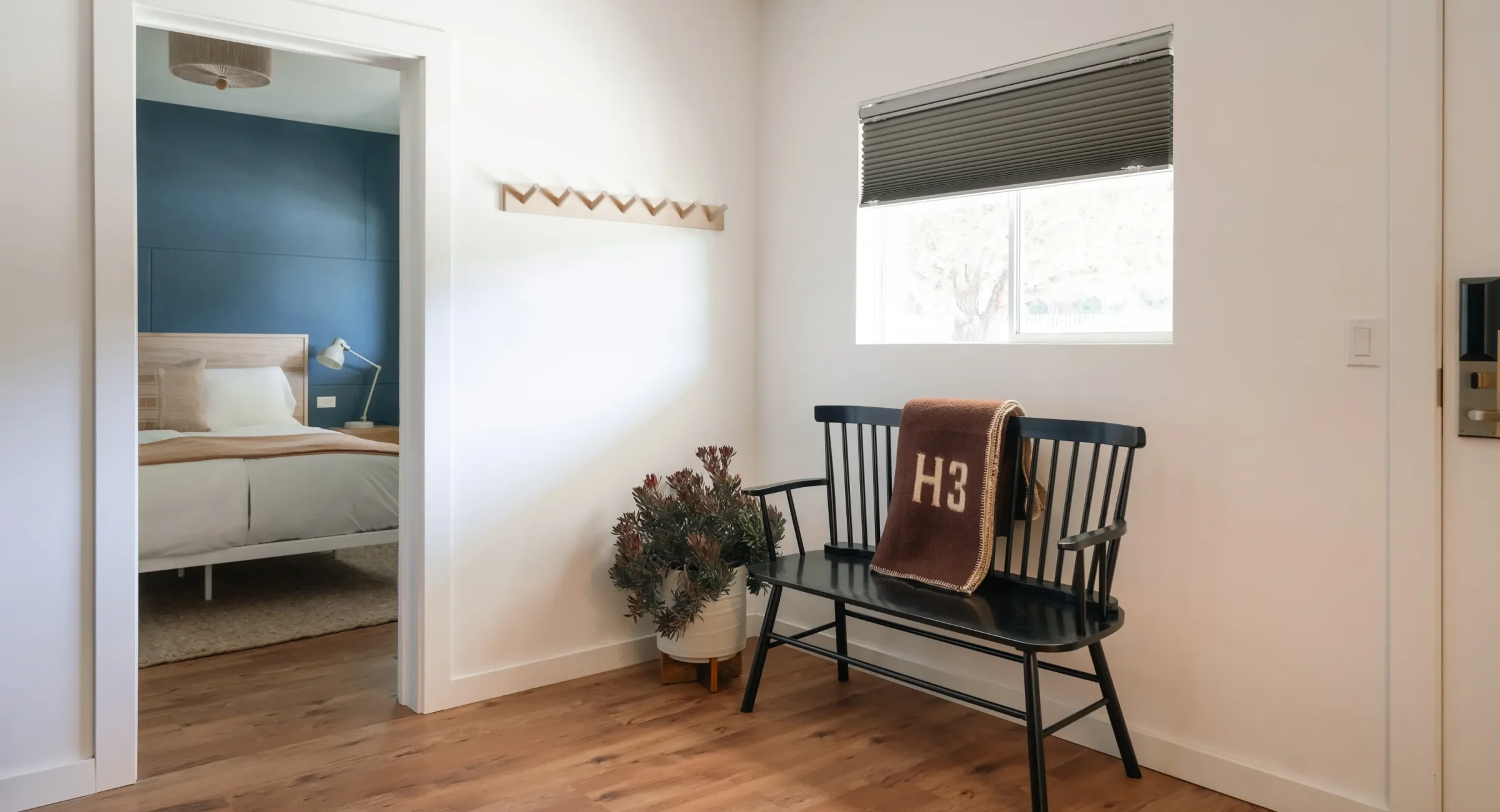 Mendocino Coast suite entry with modern bench, throw blanket, and view into king bedroom