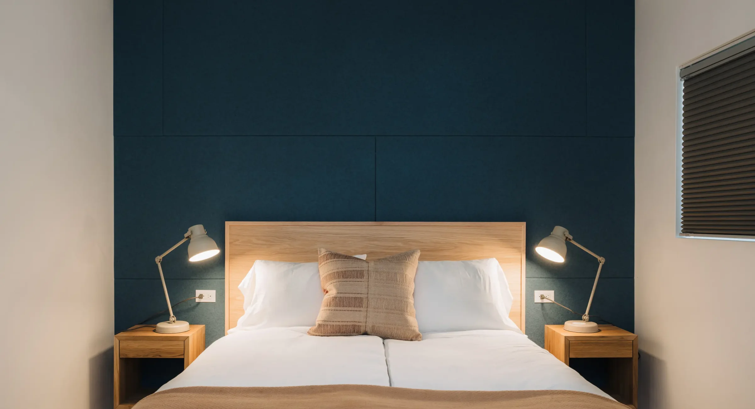 Mendocino hotel suite bedroom with king bed, blue accent wall, and modern bedside lamps