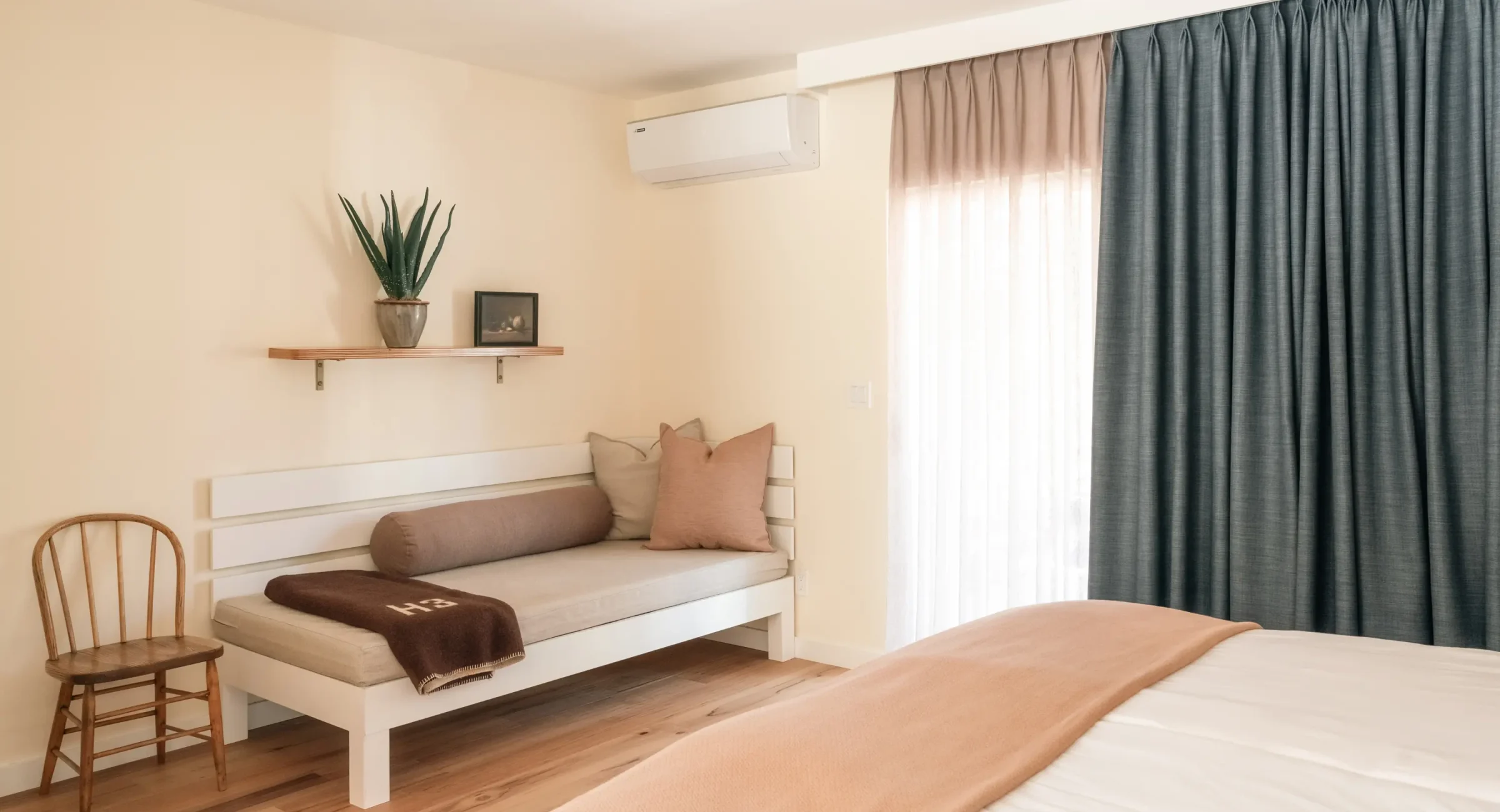 Seating area in Mendocino hotel king room with daybed, pillows, and potted plant on shelf