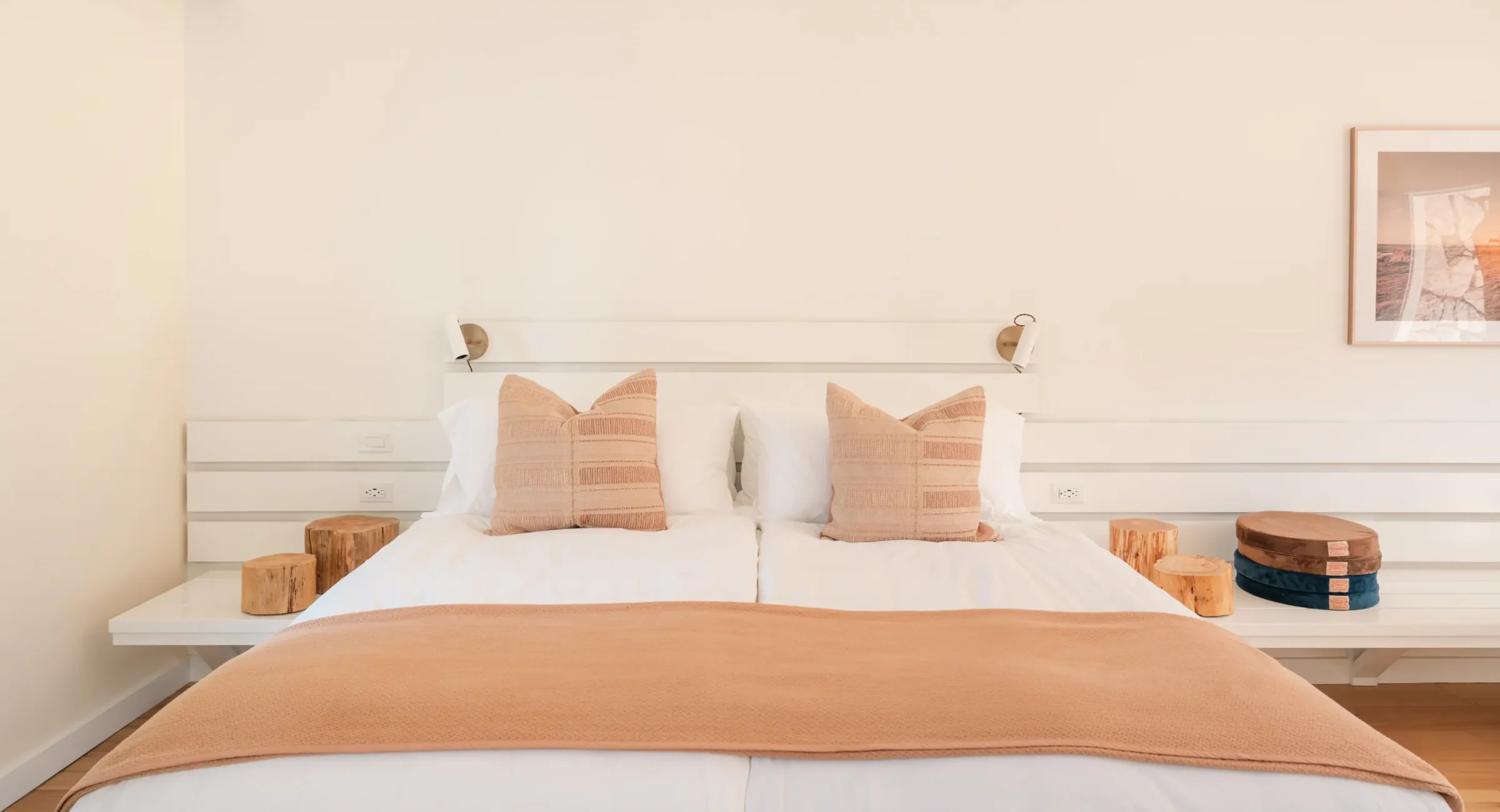 Mendocino hotel king bed with tan pillows, wood stump nightstands, and minimalist décor