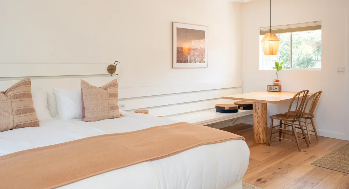 Mendocino hotel king room with bed, dining table, and wood chairs by window