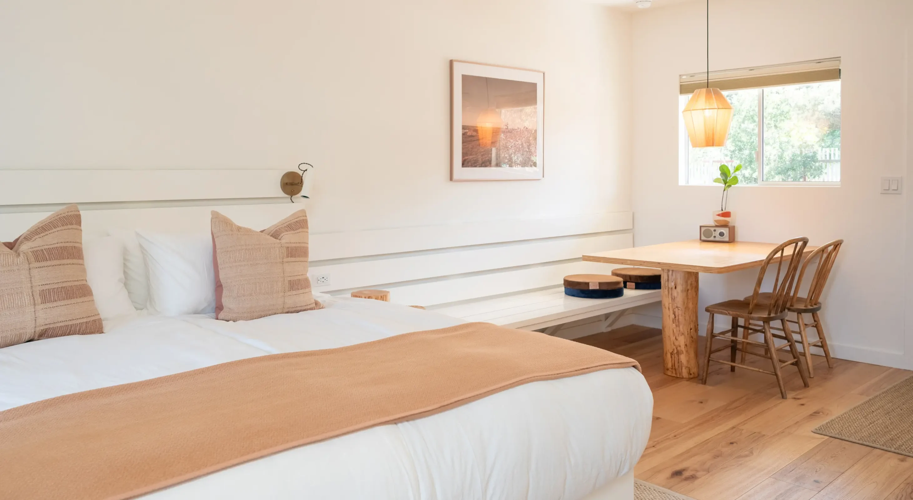Mendocino hotel king room with bed, dining table, and wood chairs by window