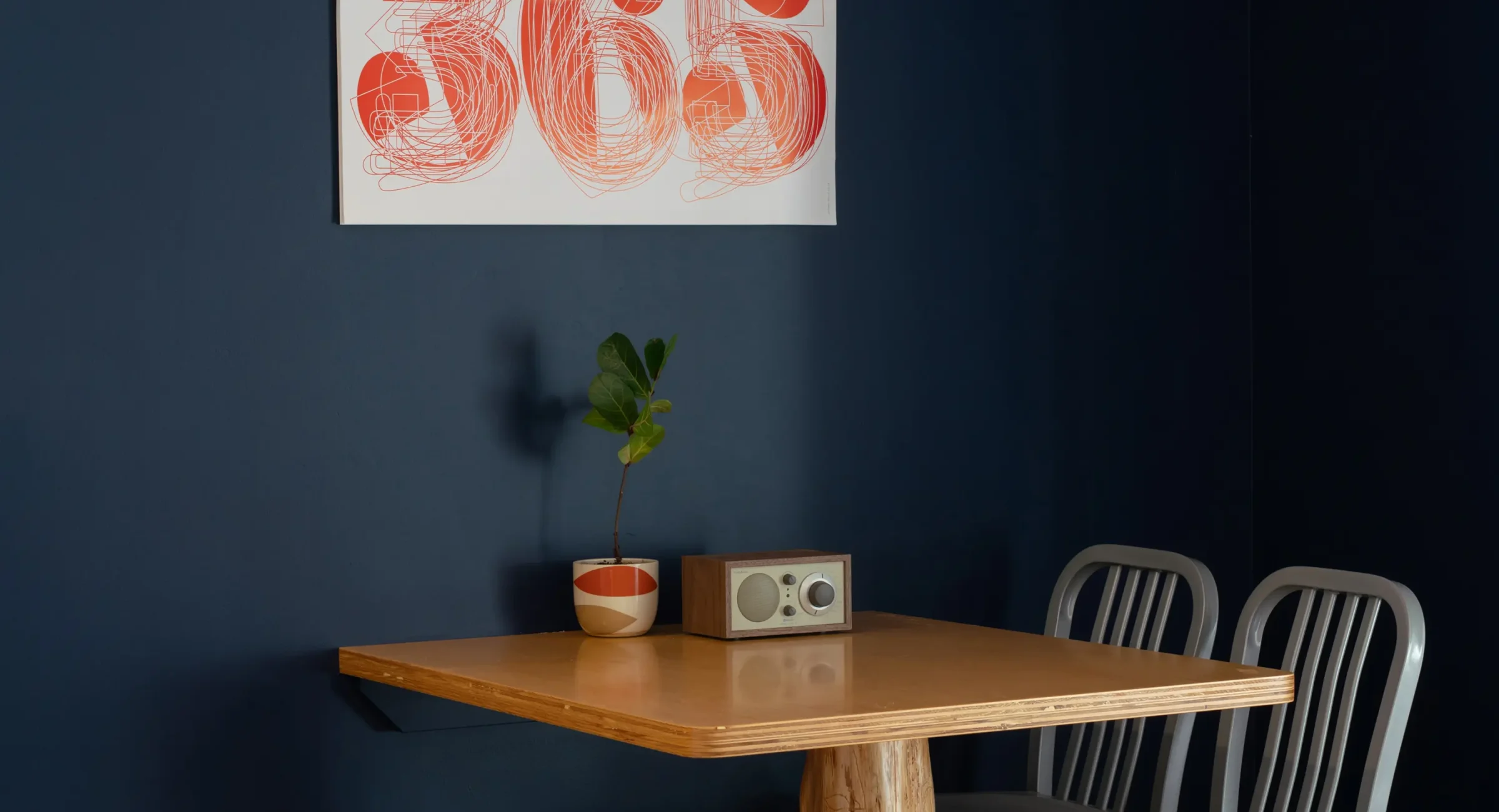 Mendocino hotel suite dining nook with wood table, navy accent wall, and modern art