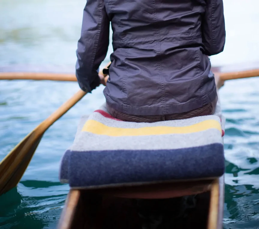 Canoer paddling on Mendocino River with view of forested banks