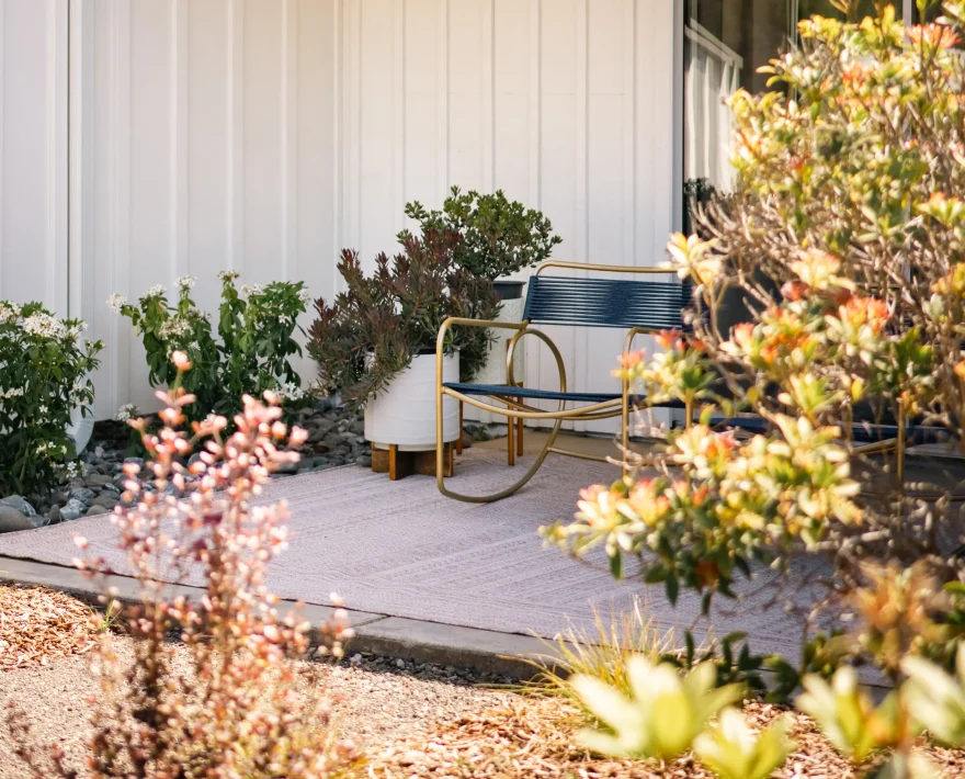 View from Mendocino coast hotel room patio with blue chairs overlooking landscaped garden