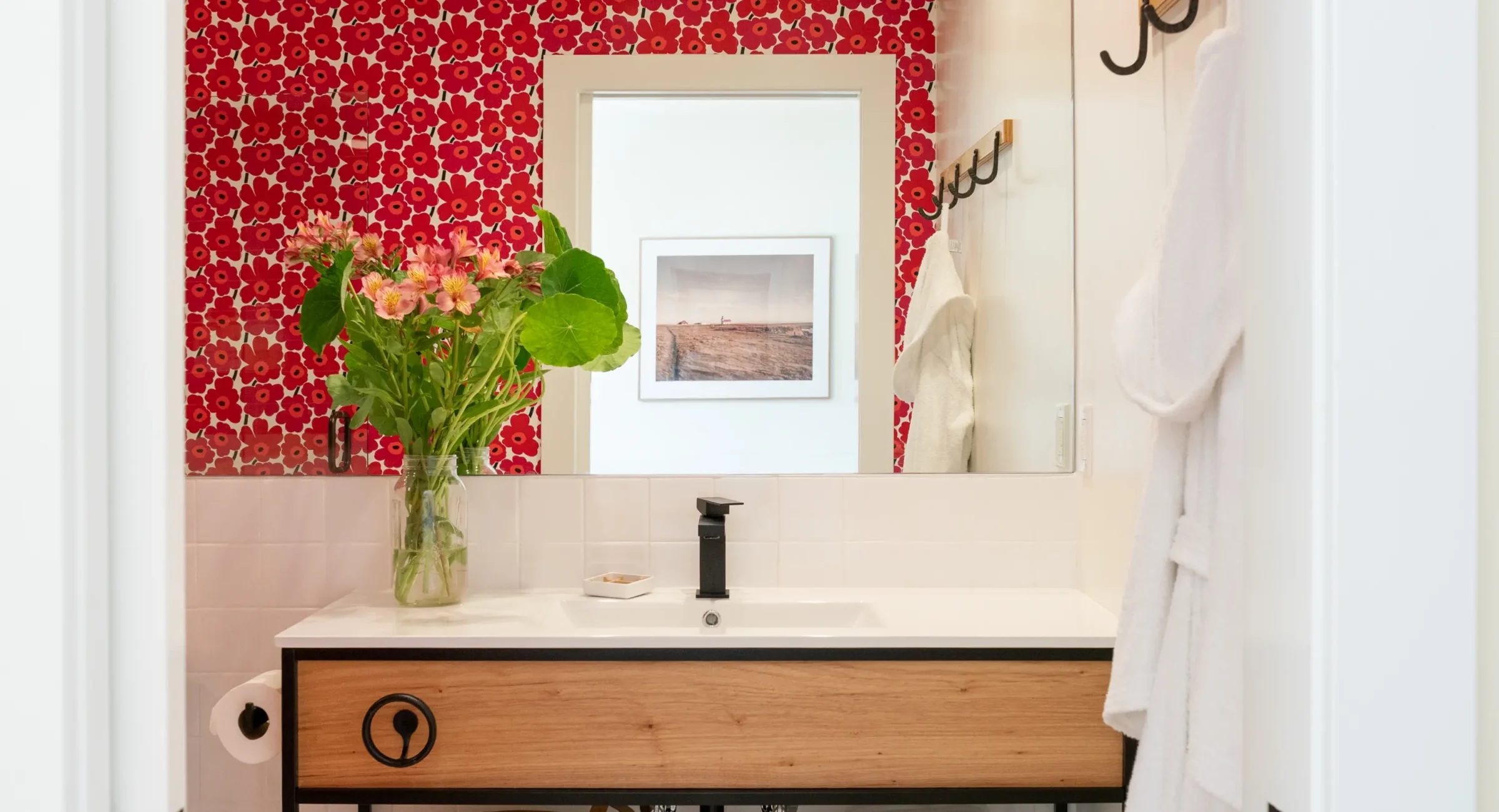 Bathroom vanity at Mendocino hotel with wood sink cabinet, mirror, and floral red tile wall