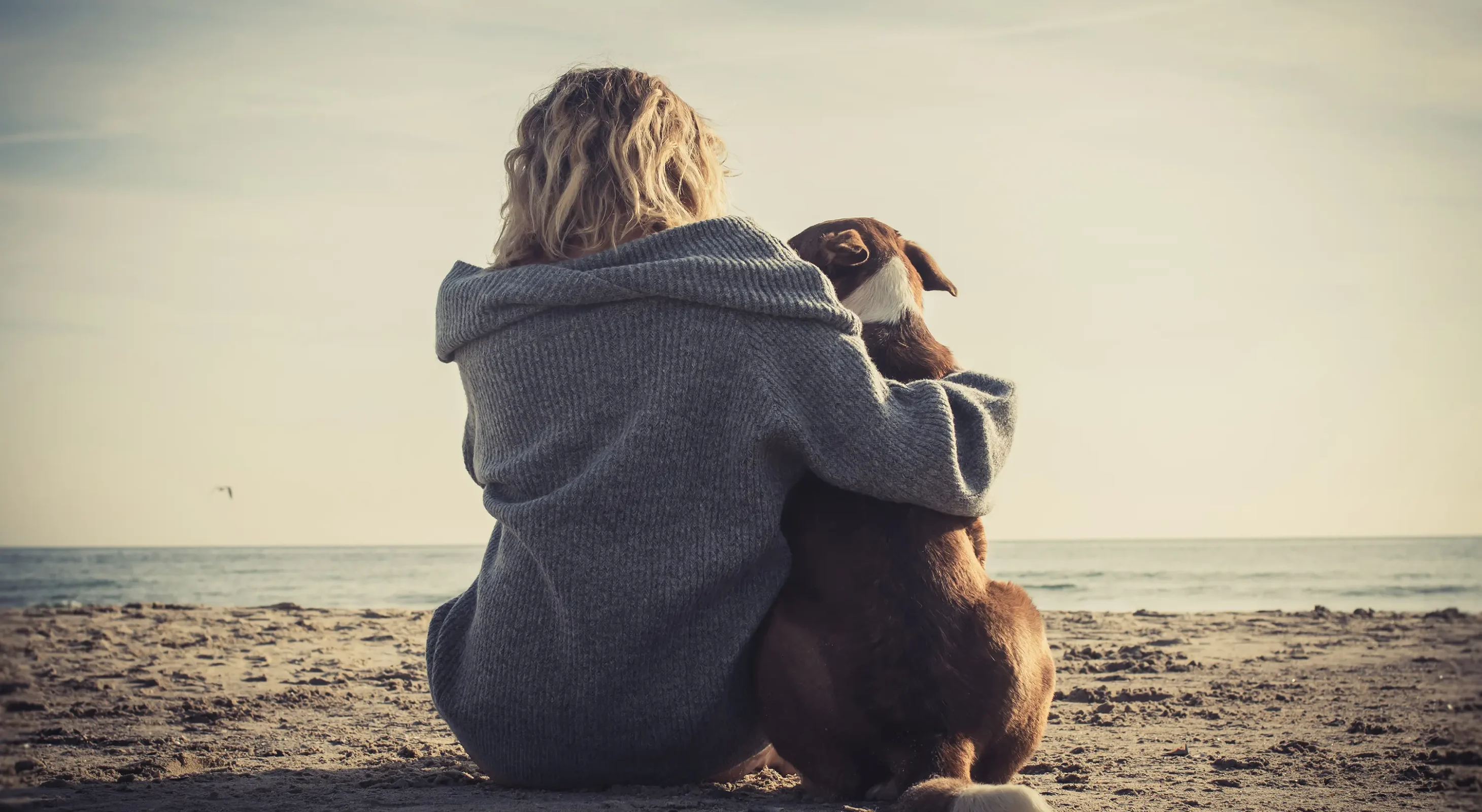 Woman hugging dog on the beach in Northern California