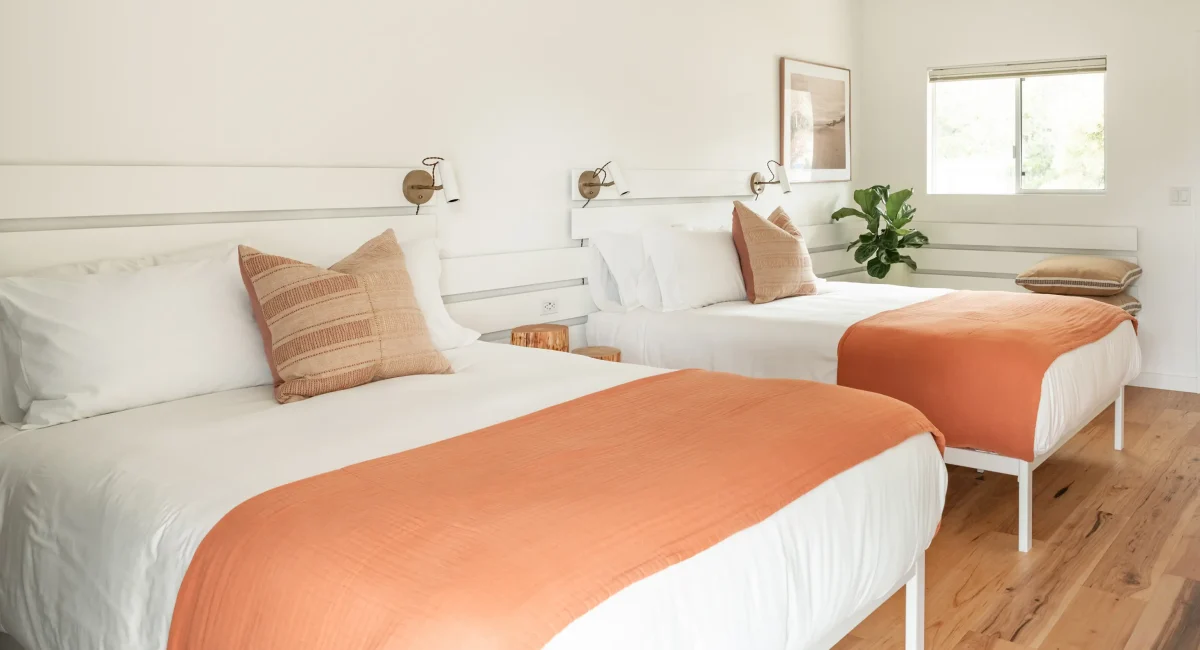 Mendocino hotel room with two queen beds, wood floors, and modern wall lighting