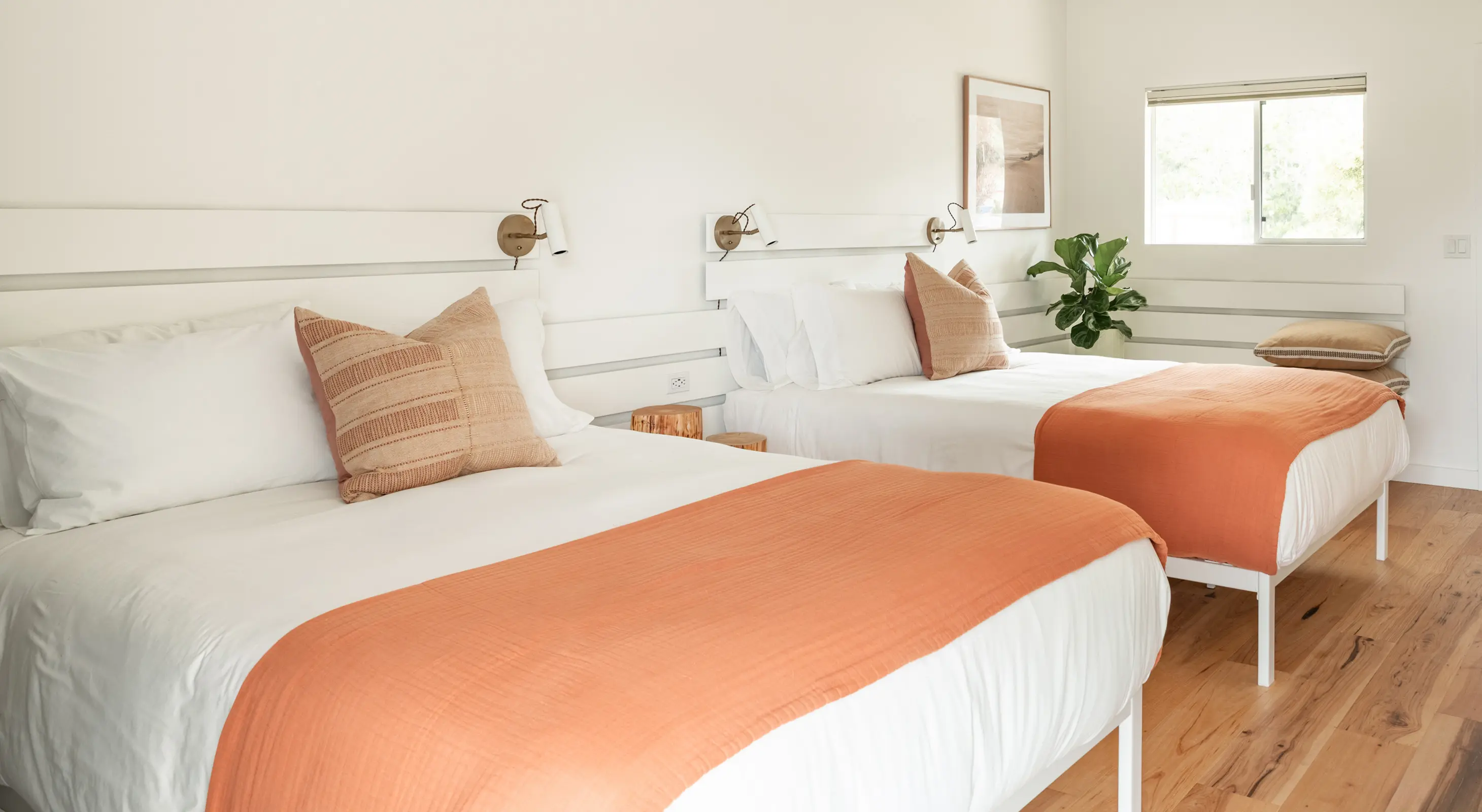 Mendocino hotel room with two queen beds, wood floors, and modern wall lighting