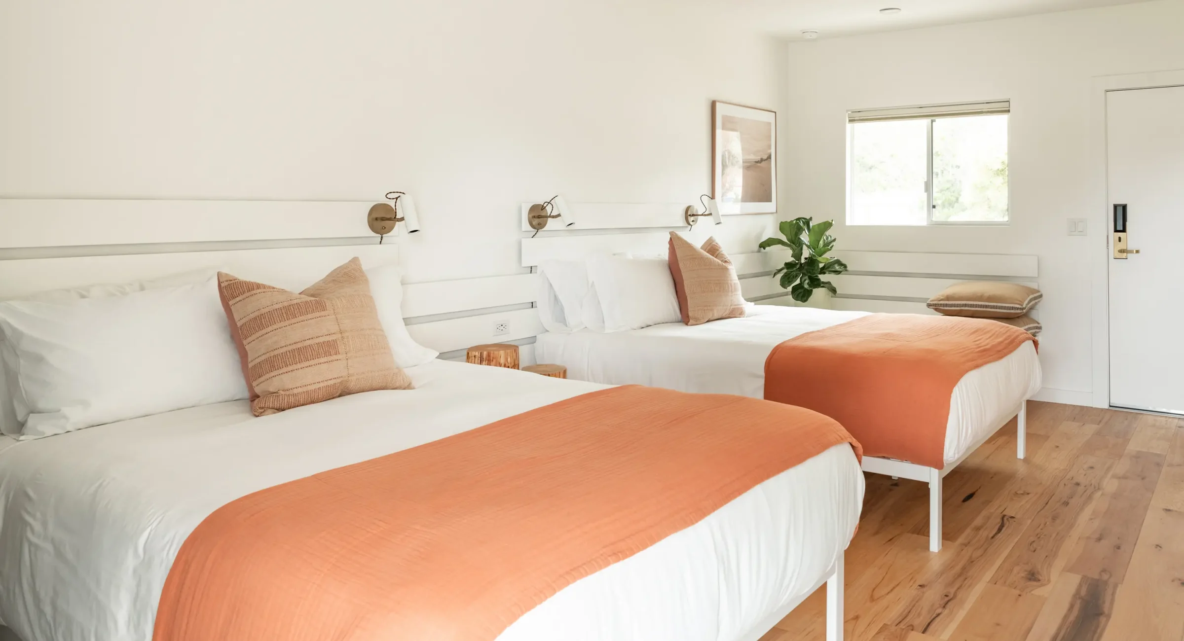 Mendocino hotel room with two queen beds, wood floors, and modern wall lighting