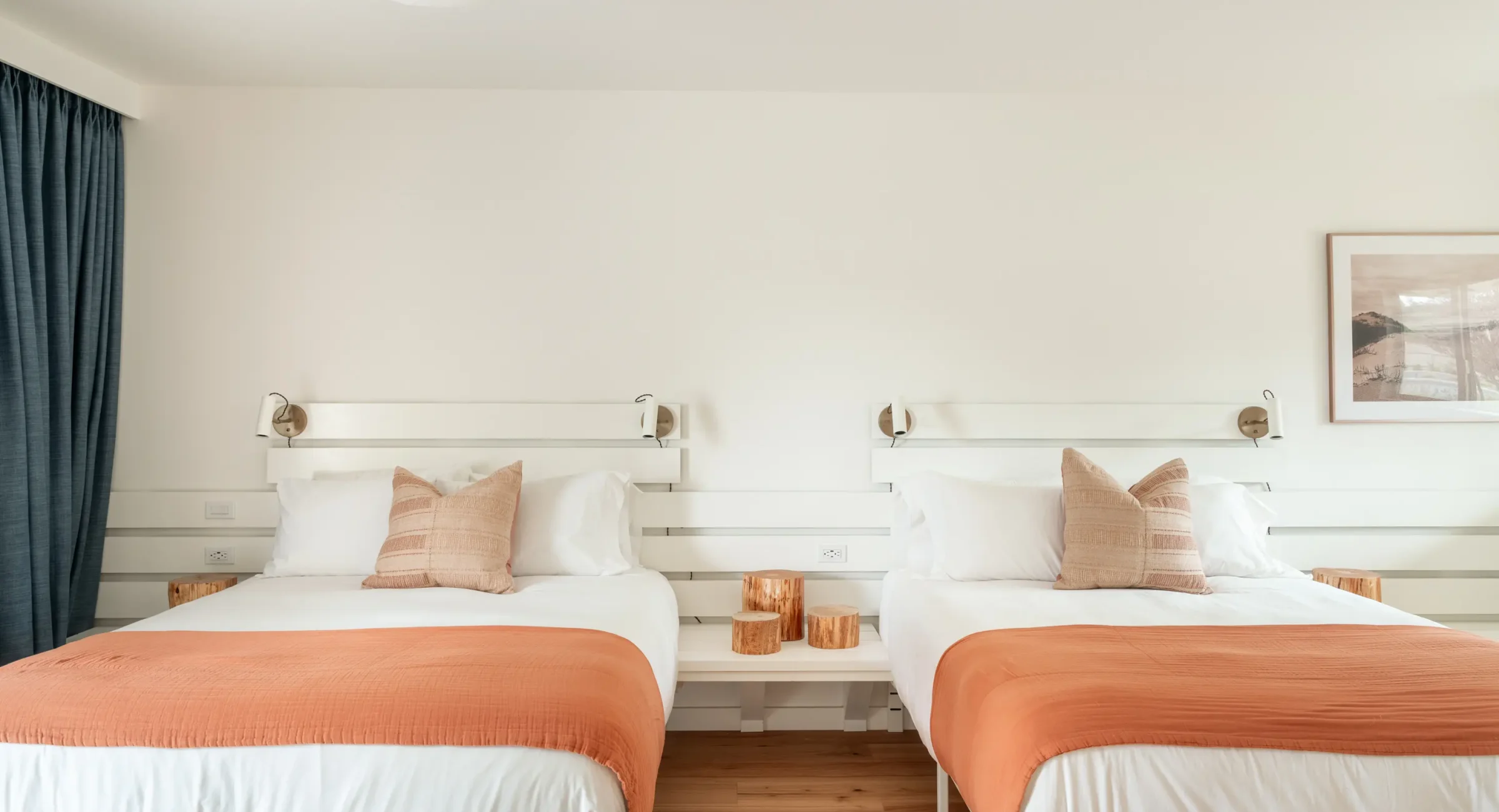 Two queen beds in Mendocino hotel room with wood stump nightstands and accent pillows