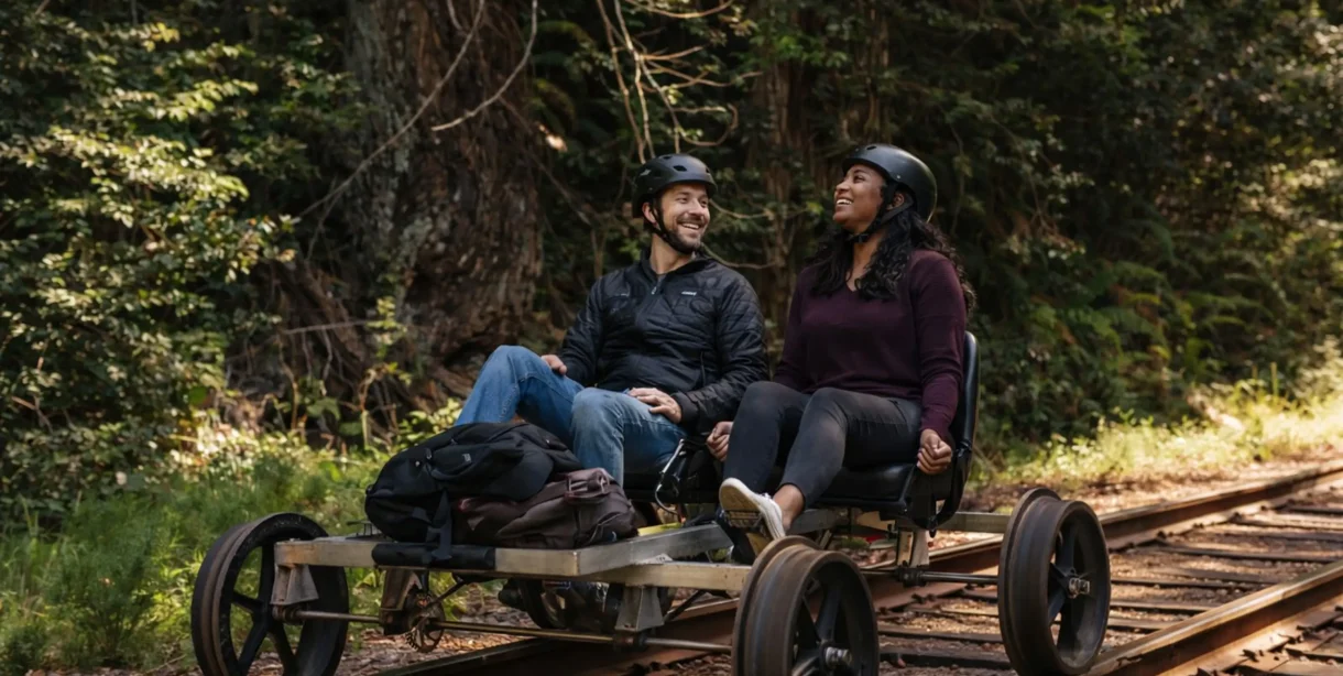 Couple pedaling through the redwoods on a railbike during a Mendocino getaway package
