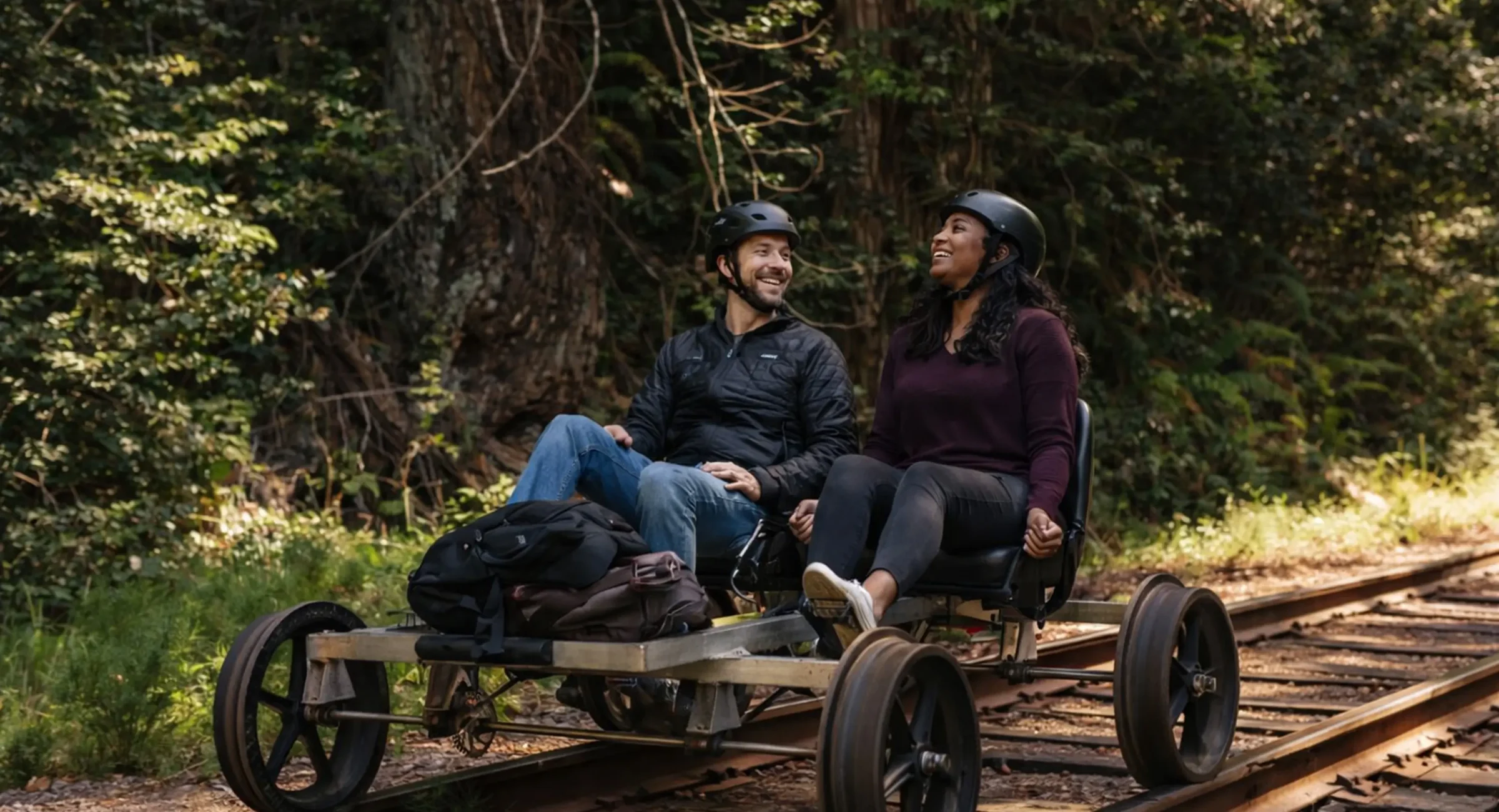 Couple pedaling through the redwoods on a railbike during a Mendocino getaway package